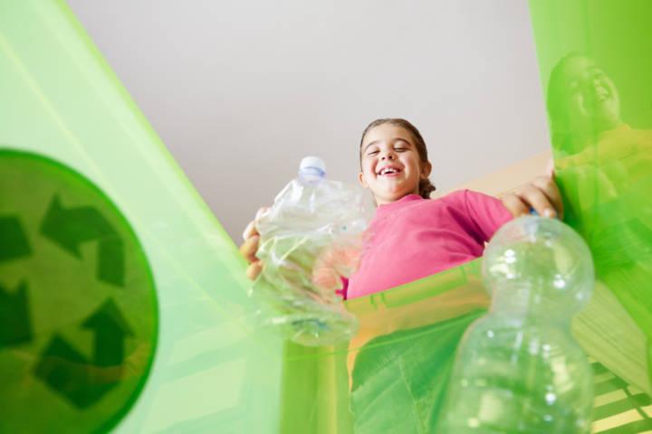 Tyttö vie muovipullon kierrätykseen.