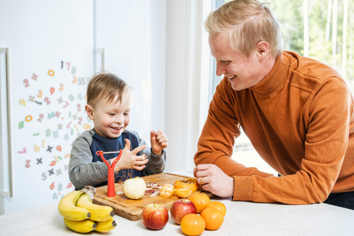 Valokuva, jossa poiska ja isä laittavat ruokaa keittiössä.