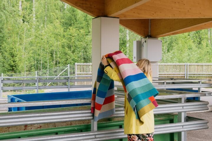 Henkilö kantaa mattoa lajittelukeskuksessa